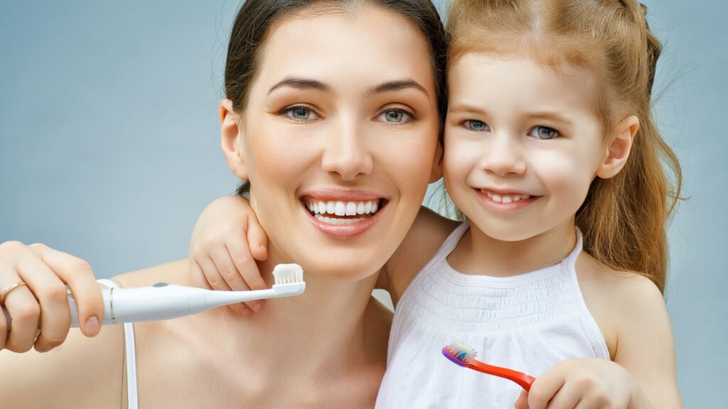 Madre e hija pequeña sonriendo mientras sostienen sus cepillos de dientes